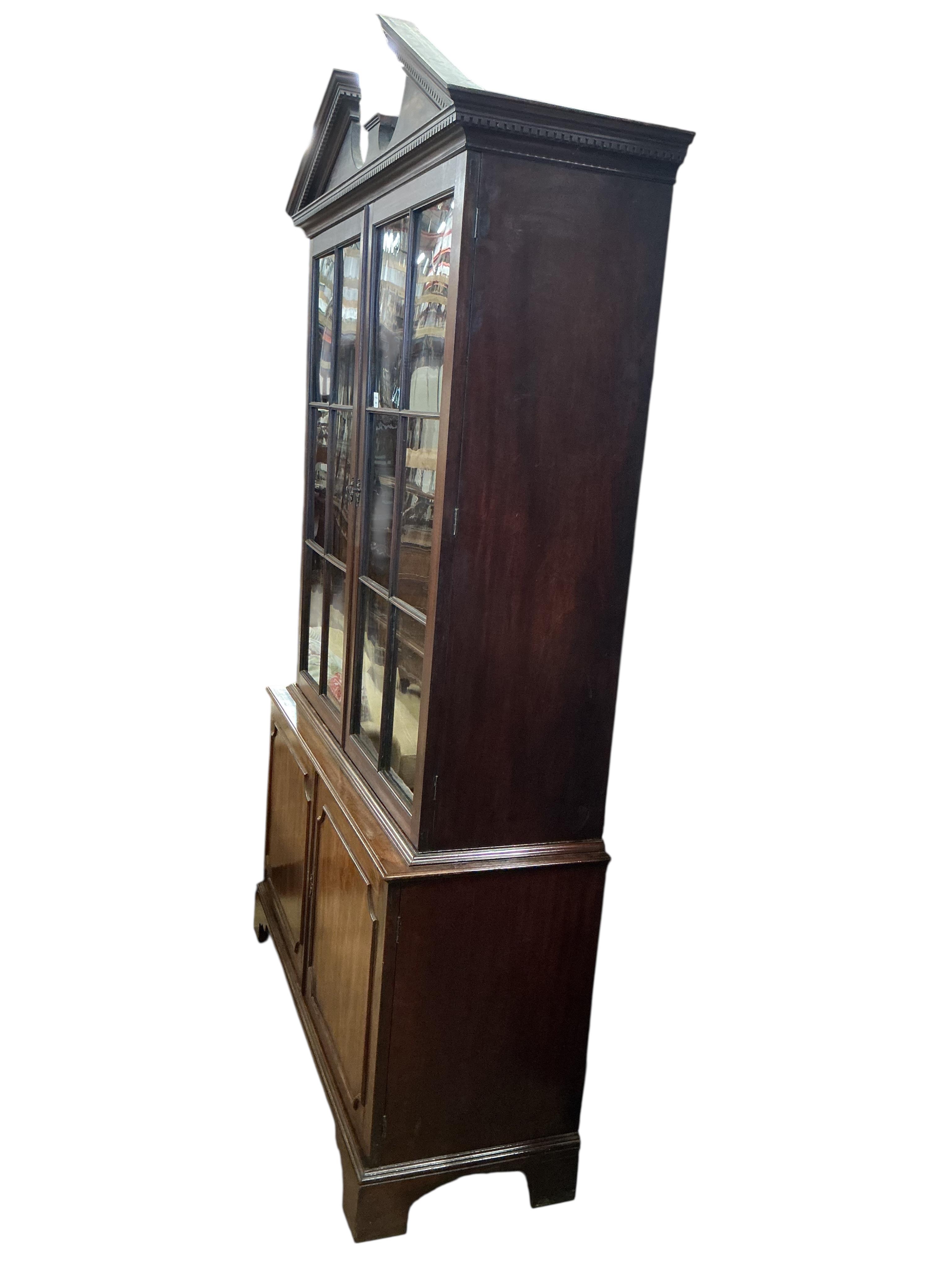 A George III mahogany library bookcase, the top surmounted with a broken architectural pediment, width 132cm, depth 47cm, height 234cm